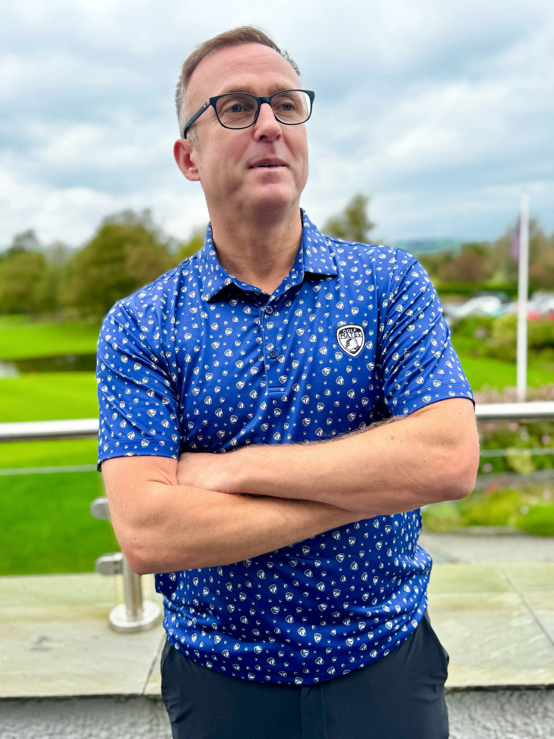 Liam from Golfmates wearing the custom polo sublimated with the golfmates logo. Standing in front of a golf course.